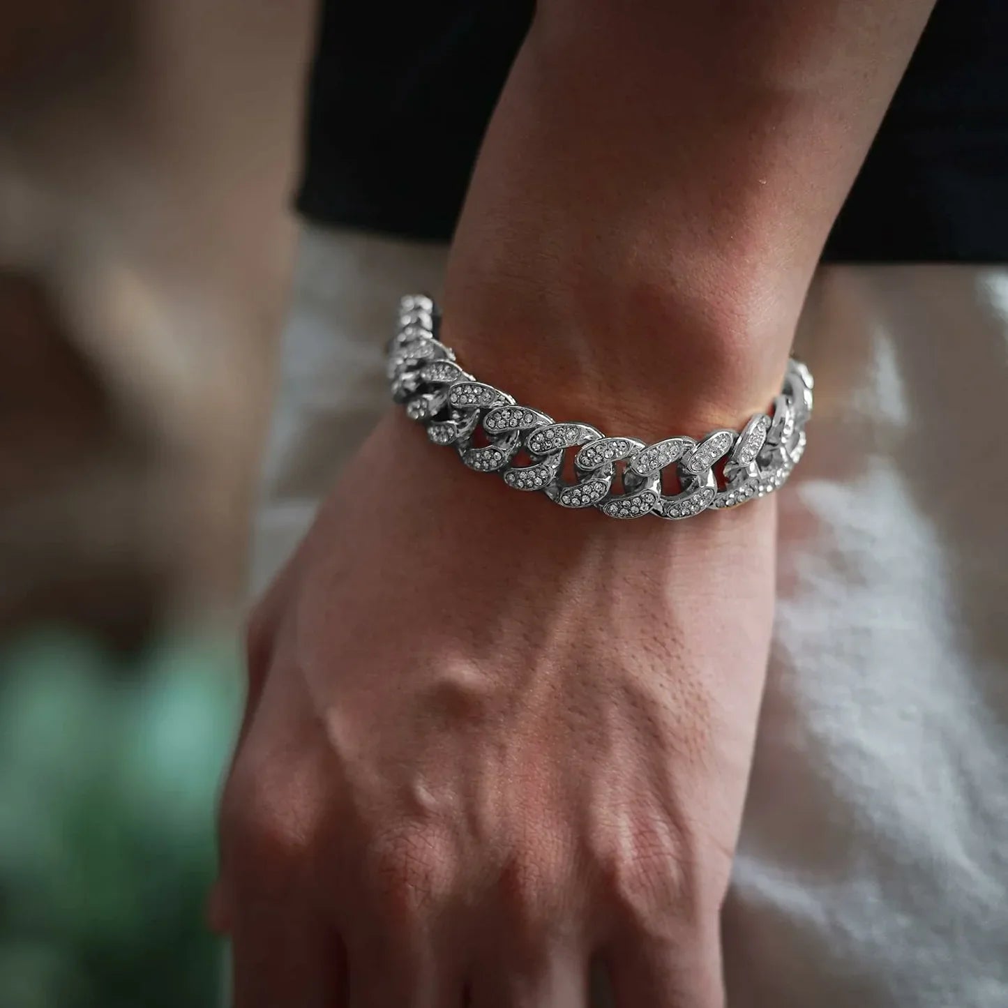 Close-up of a wrist wearing a silver bracelet with red stones on a blurred background